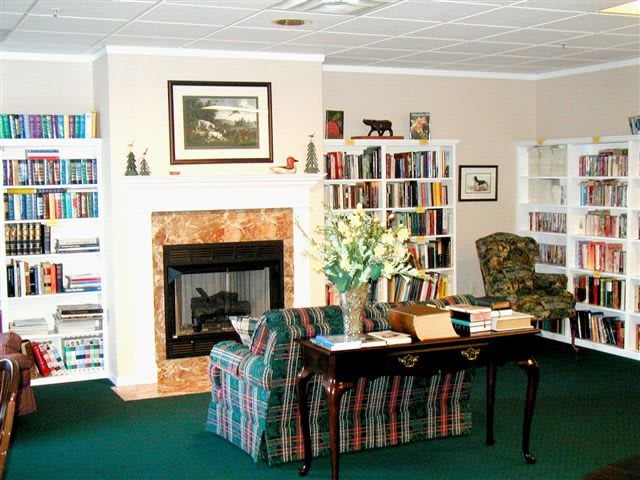 A cozy living room featuring a fireplace, bookshelves filled with books, and comfortable seating arrangements.