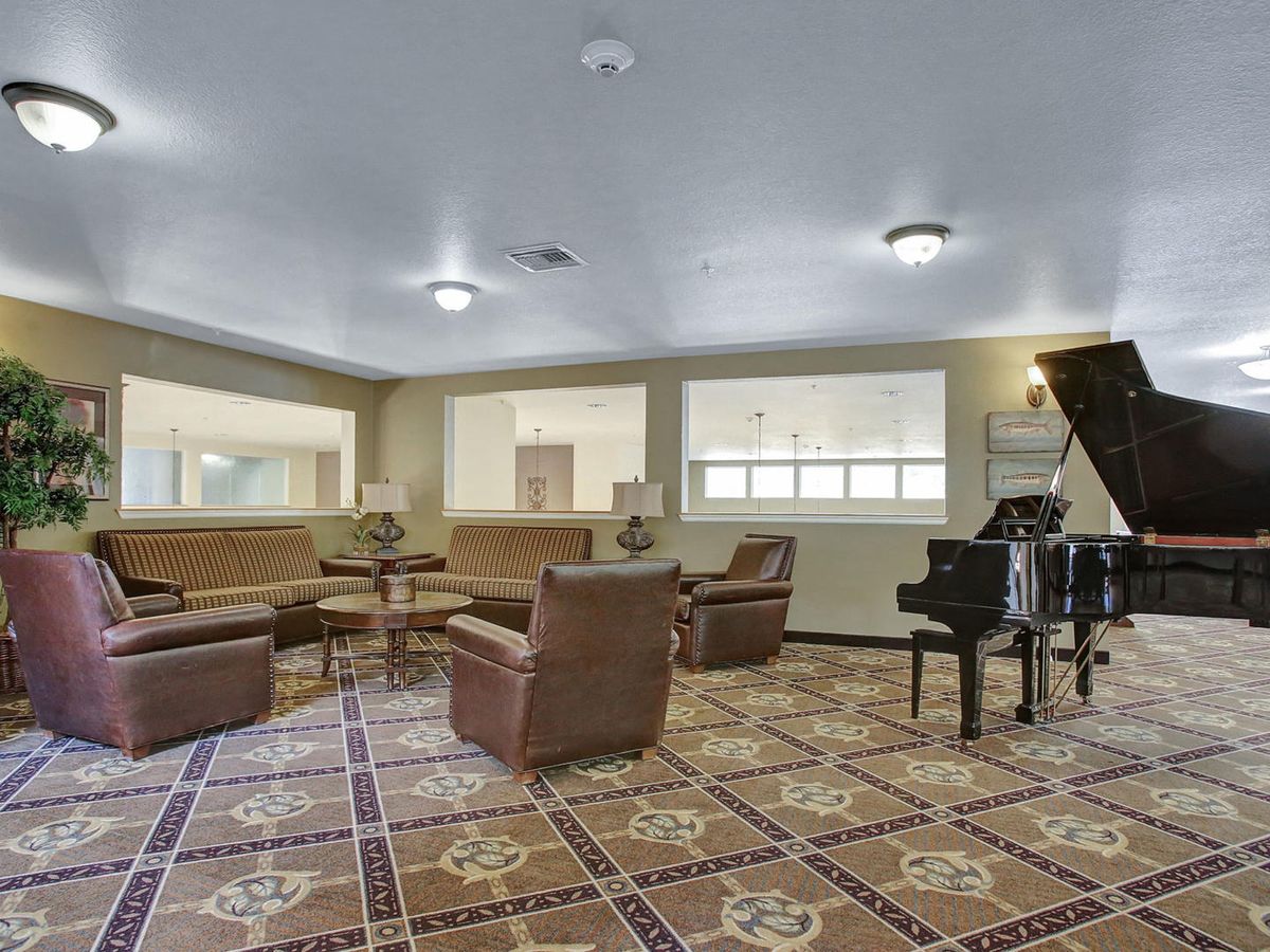 A cozy lounge area featuring comfortable seating, a grand piano, and decorative floor tiles.