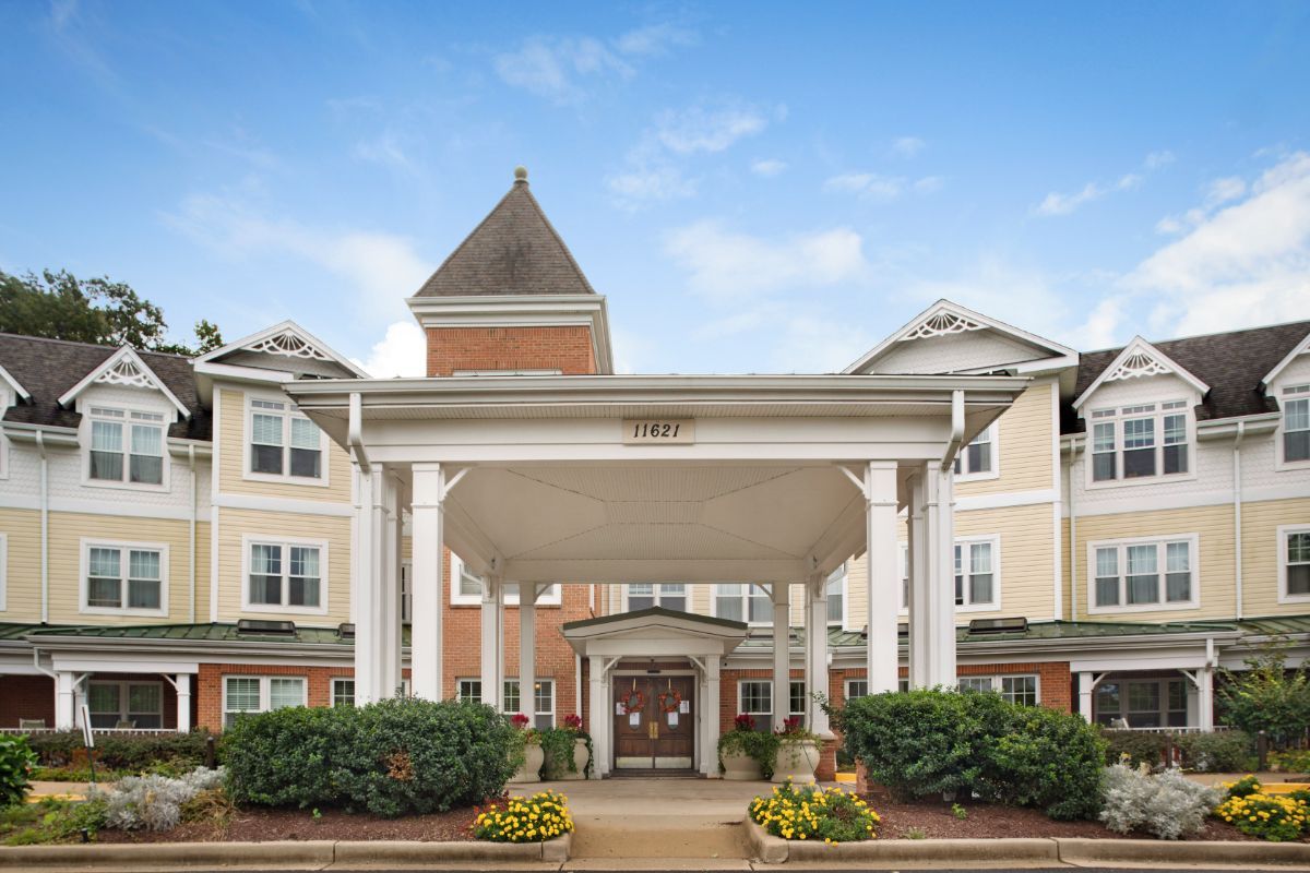 A view of a large building entrance with columns and landscaping.