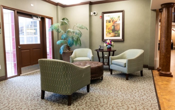 A cozy waiting room with comfortable chairs, a small table, and decorative elements including a plant and artwork.