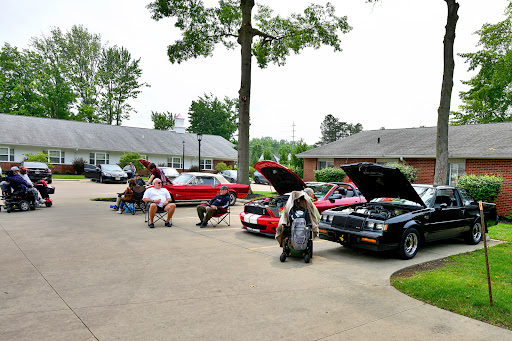 Car enthusiasts working on their vehicles in a parking area.
