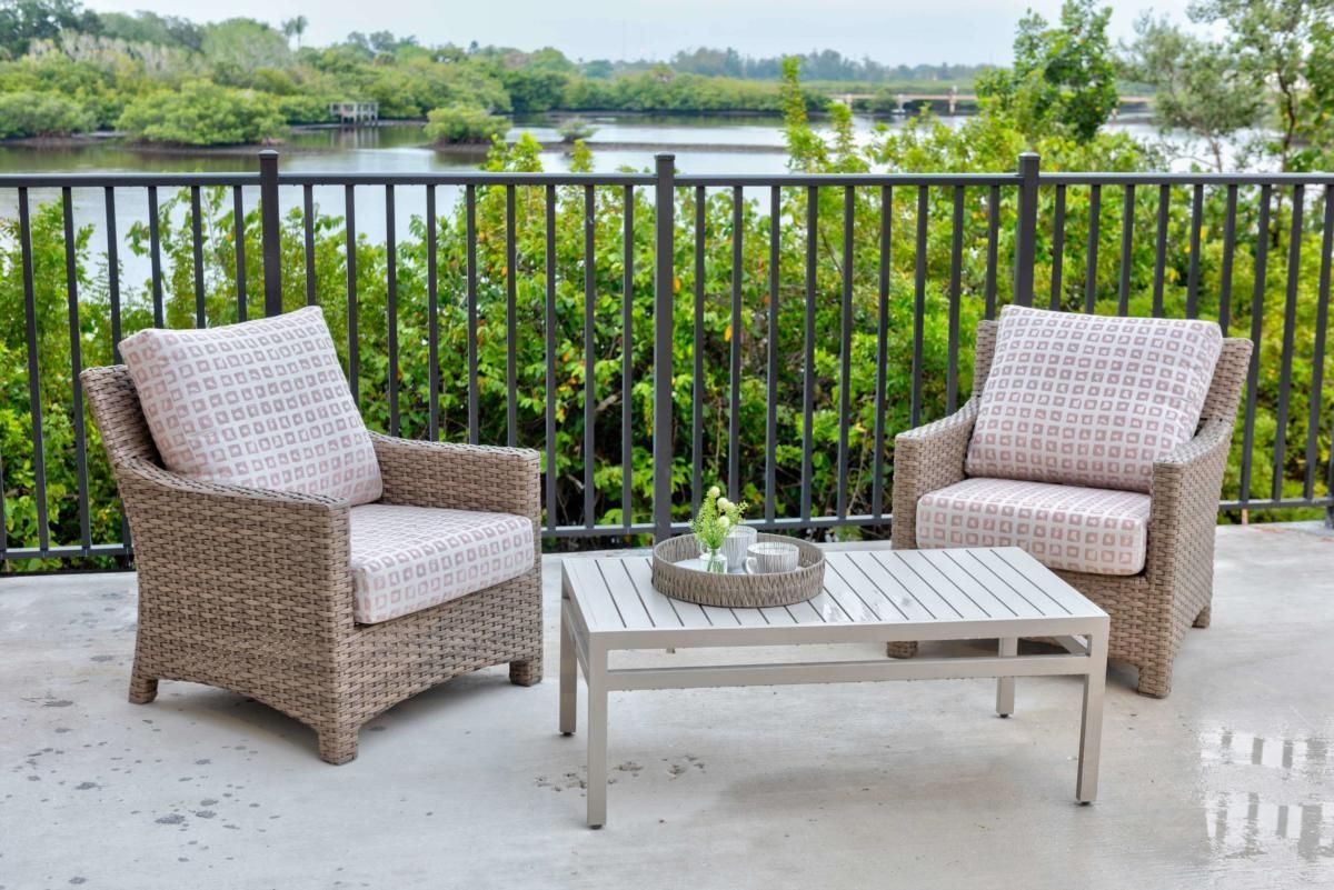 A cozy outdoor seating area with wicker chairs and a table overlooking a river.