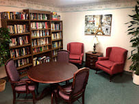 A cozy reading room with a round table, chairs, and bookshelves.
