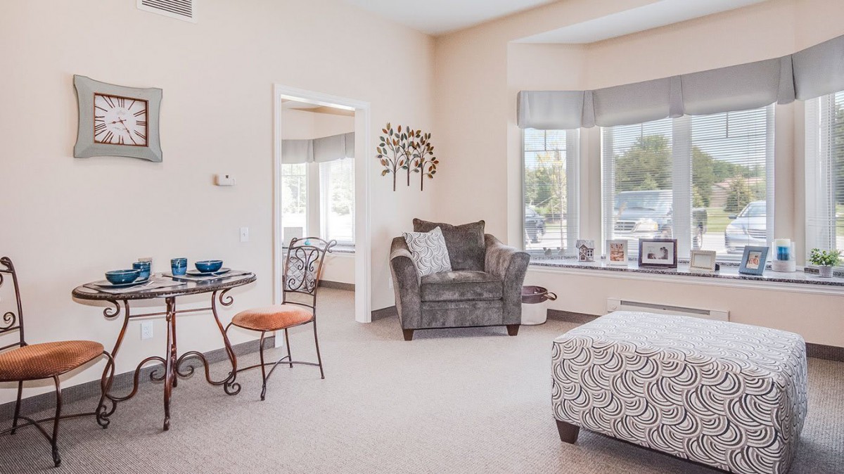 A cozy living room with a plush armchair and a small dining table by the window.