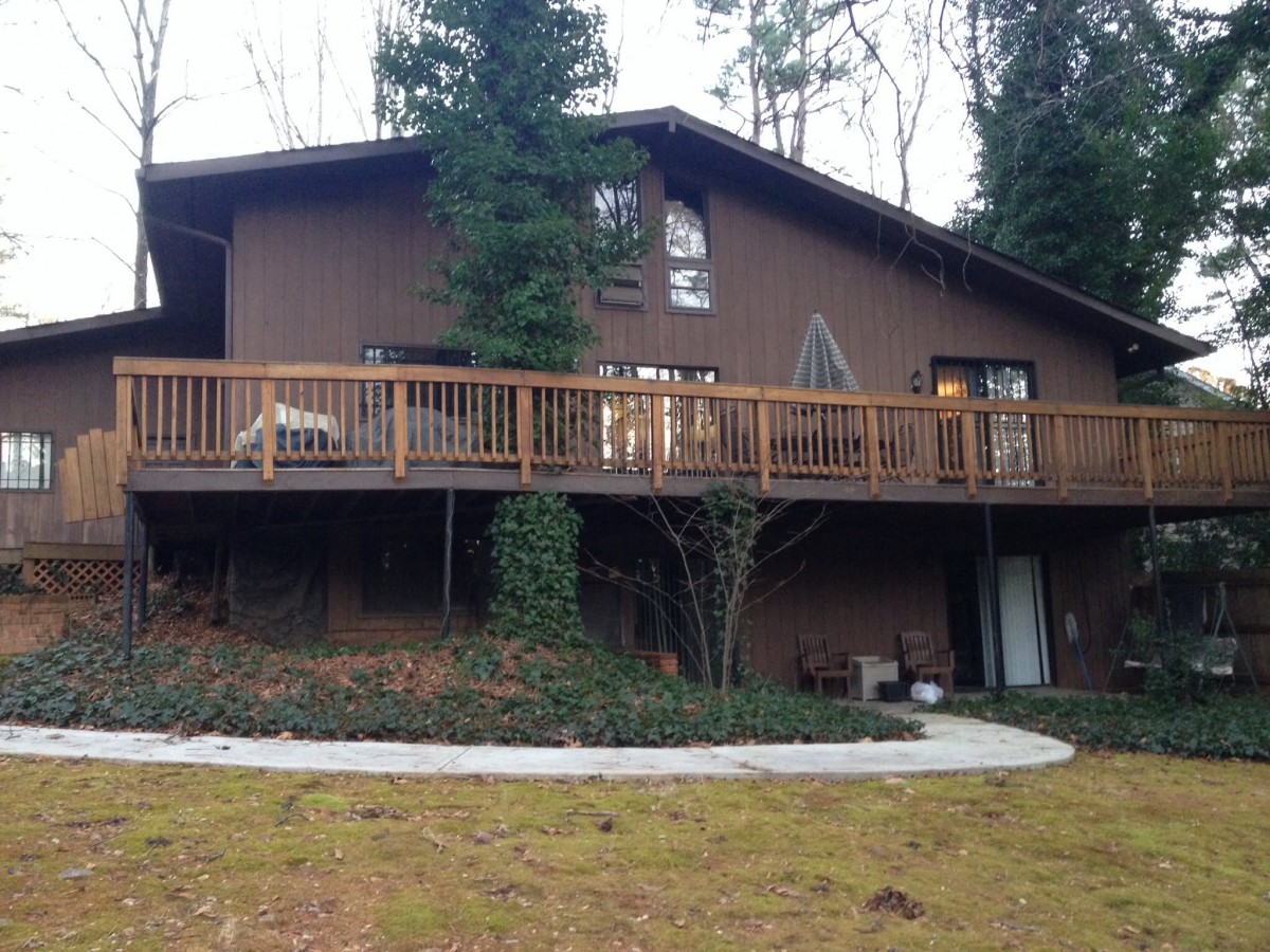 A rustic house with a wooden deck surrounded by trees.