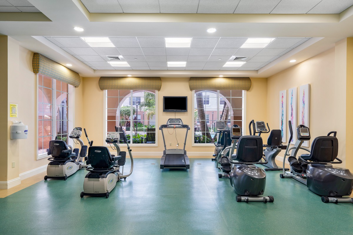 A well-equipped gym with various exercise machines and a treadmill in the center.