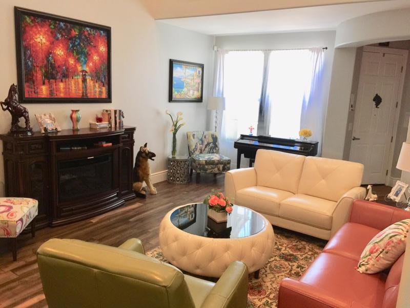 A cozy living room with modern furniture, featuring a piano and colorful artwork.