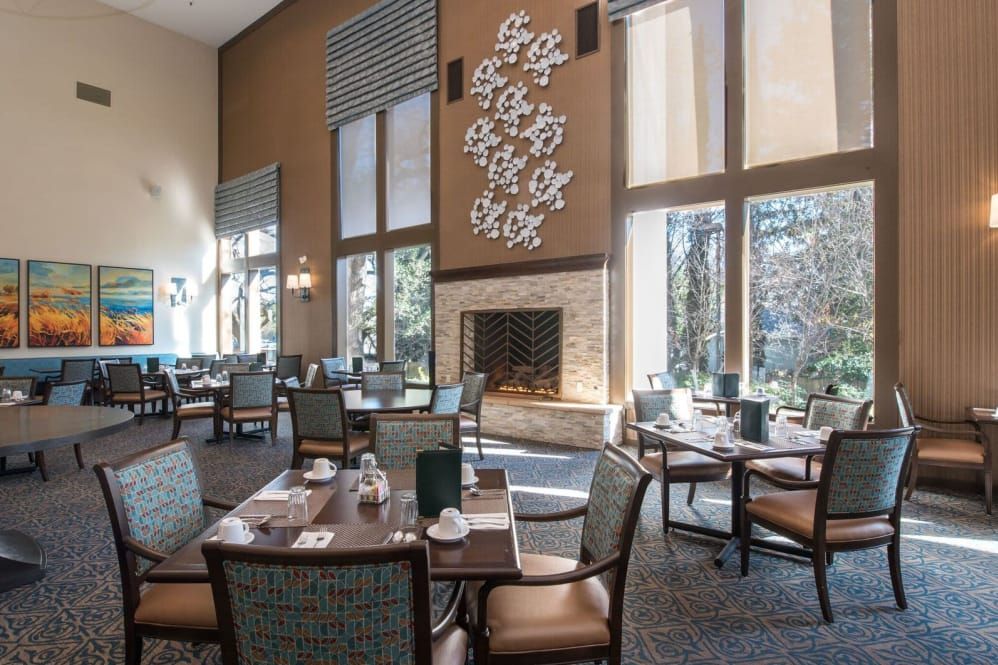 A spacious dining room with elegant decor, featuring large windows and a central fireplace.
