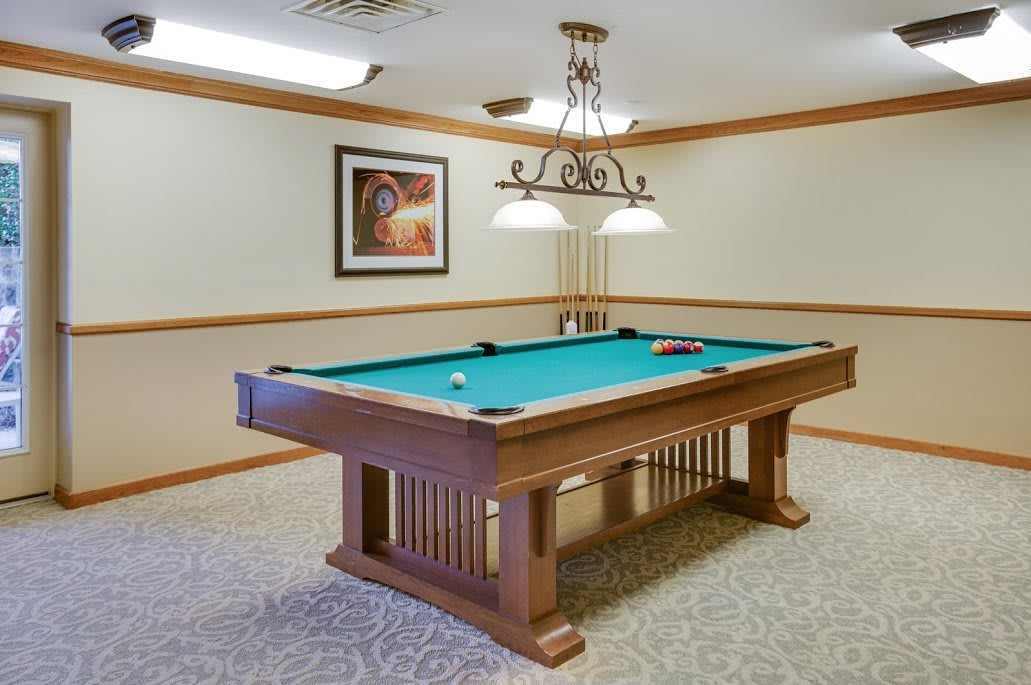 A recreation room featuring a pool table with overhead lighting.