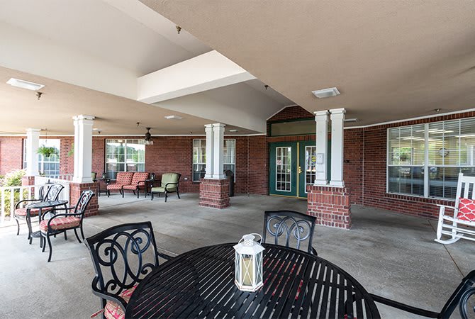 A covered outdoor patio area with tables, chairs, and a decorative lantern.