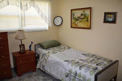 A cozy and simple bedroom featuring a single bed, nightstand, wall clock, and a piece of artwork.