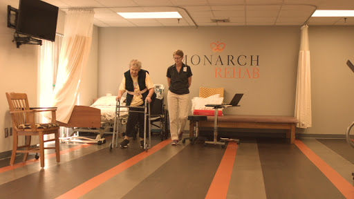 An elderly patient receiving assistance during rehabilitation at a healthcare facility.