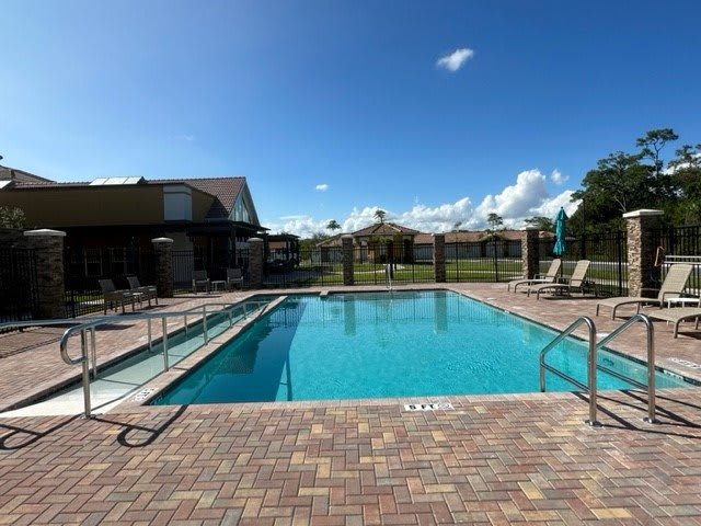 A sunny day by the outdoor swimming pool, surrounded by a patio with lounge chairs.