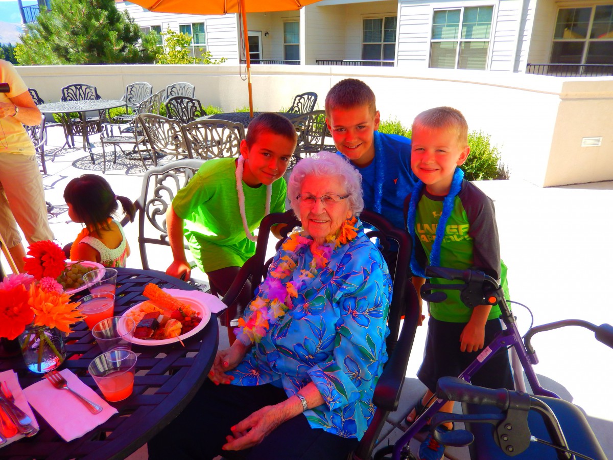 A family gathering outdoors with an elderly woman and children enjoying a meal together.