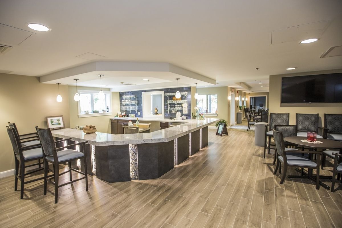 A modern kitchen and bar area featuring sleek countertops, stylish lighting, and wooden flooring.