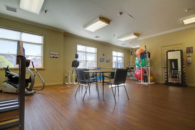 A spacious gym room with exercise equipment and a seating area.