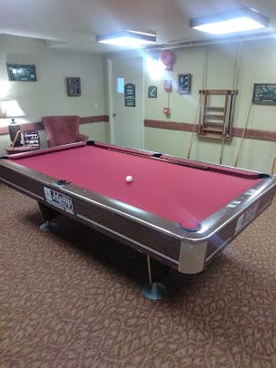 A billiards room with a red-felt pool table and various decor.
