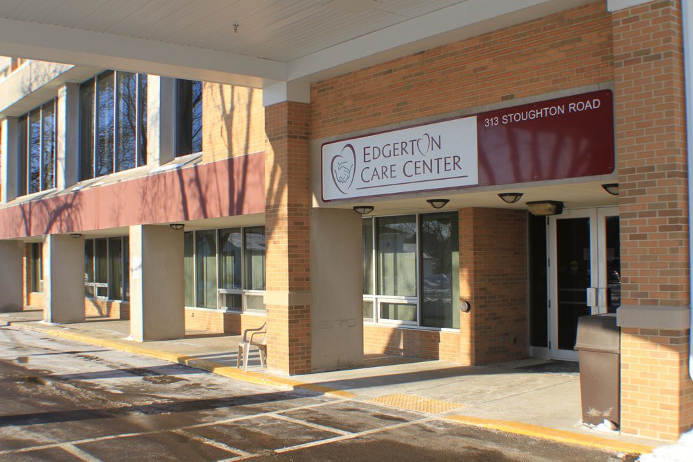 An exterior view of a clinic entrance with prominent signage and adjacent parking spaces.