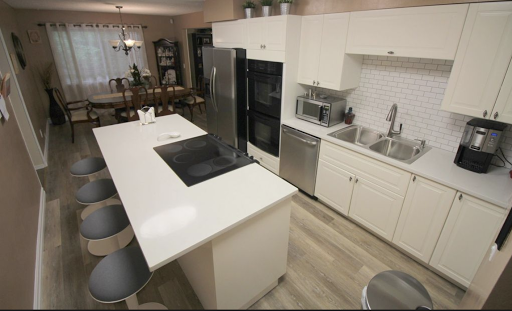 A modern kitchen showcasing a sleek design with white cabinetry and an island for cooking and dining.