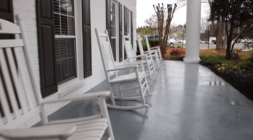 A row of white rocking chairs on a porch, perfect for relaxation.