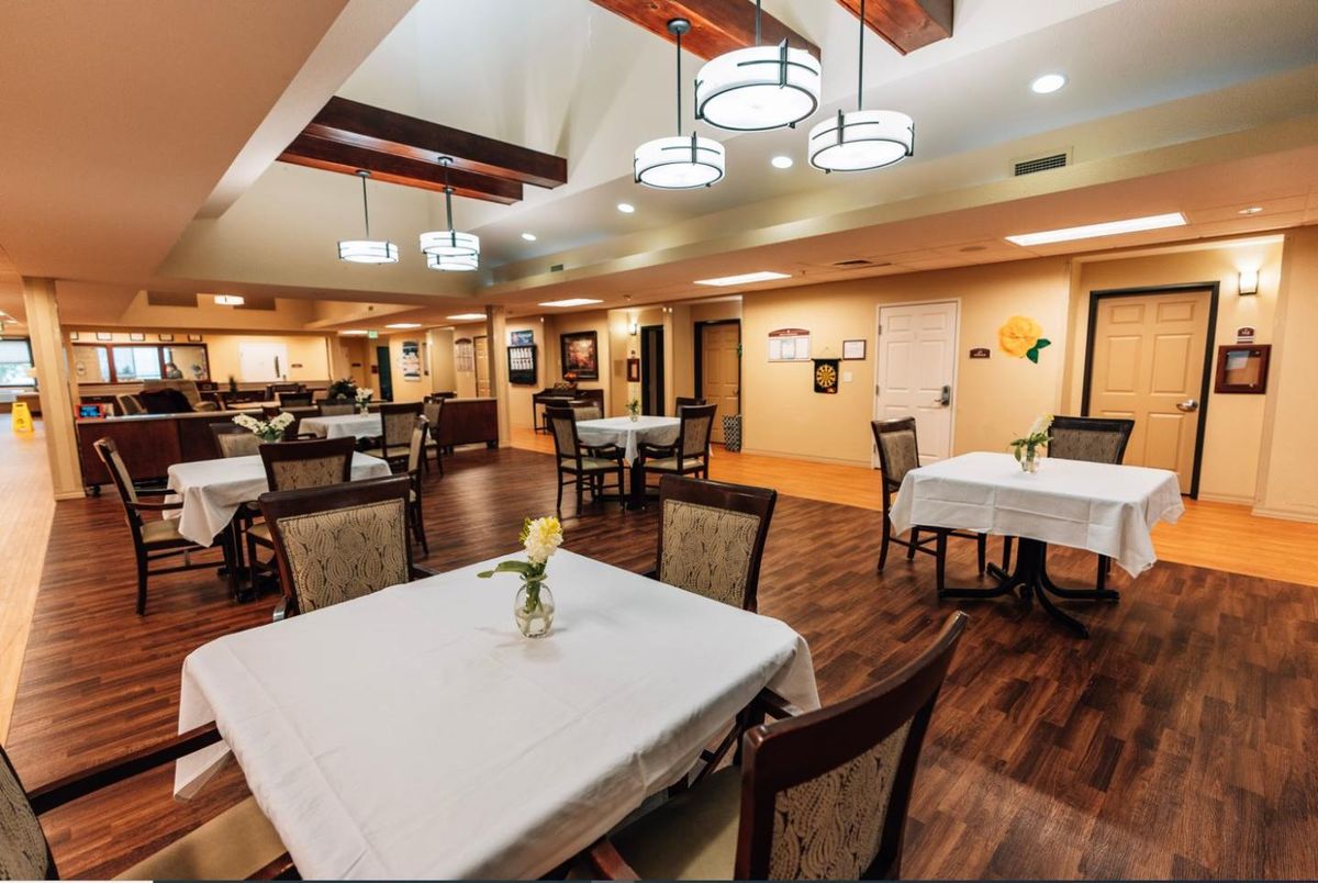 A well-lit dining area with neatly arranged tables and chairs, featuring elegant lighting fixtures.