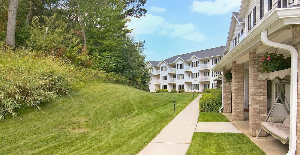 A well-maintained apartment complex with a lush green lawn and surrounding trees.