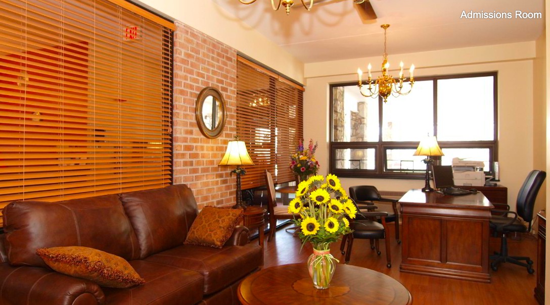 A cozy living room with a brick wall, leather sofa, and sunflowers on a wooden table.