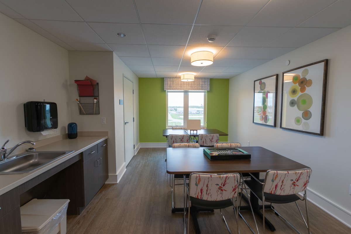 A modern dining area featuring bright green accents and wood flooring, adjacent to a compact kitchen.