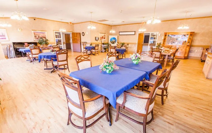 A spacious dining area with tables covered in blue tablecloths and decorated with flower arrangements.