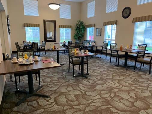 A spacious dining room with neatly arranged tables and chairs, featuring large windows and elegant decor.