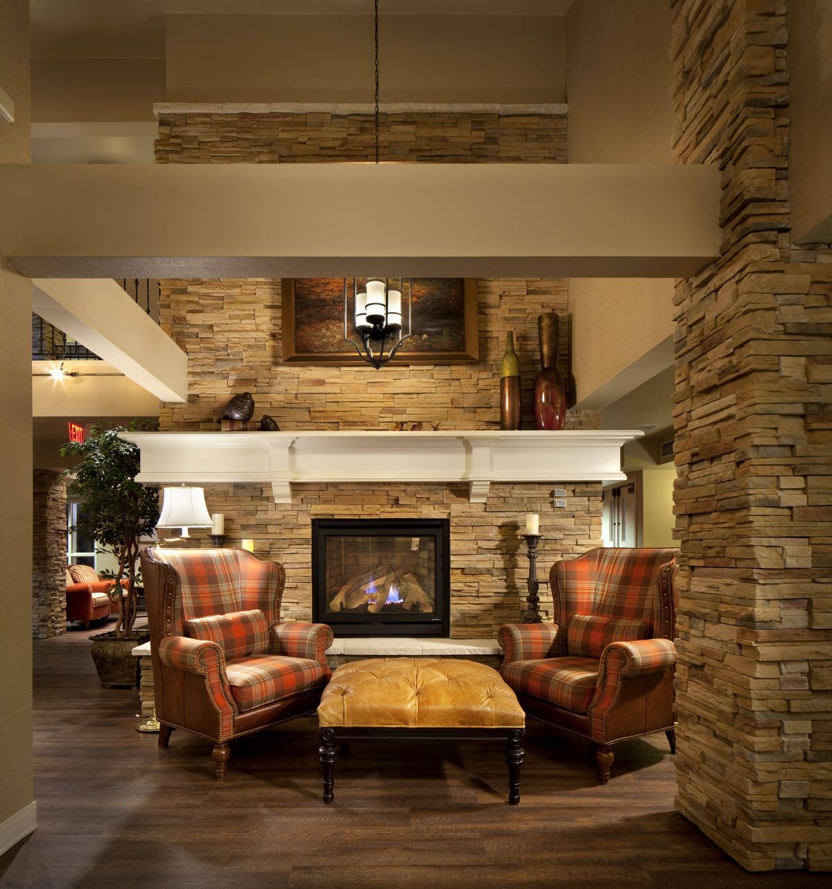 A cozy lounge featuring a stone fireplace surrounded by wooden furniture.