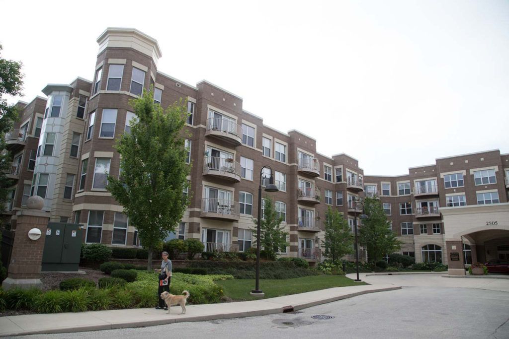 A modern apartment building with landscaped grounds and a sidewalk.