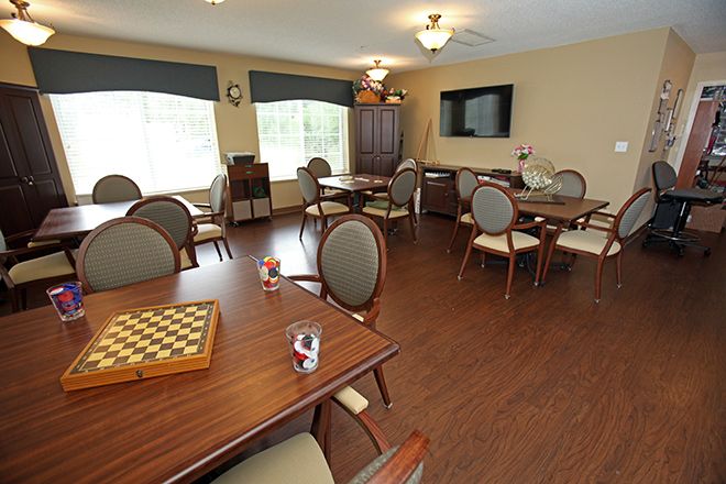 A cozy games room with several tables and chairs, featuring a chessboard and a television.