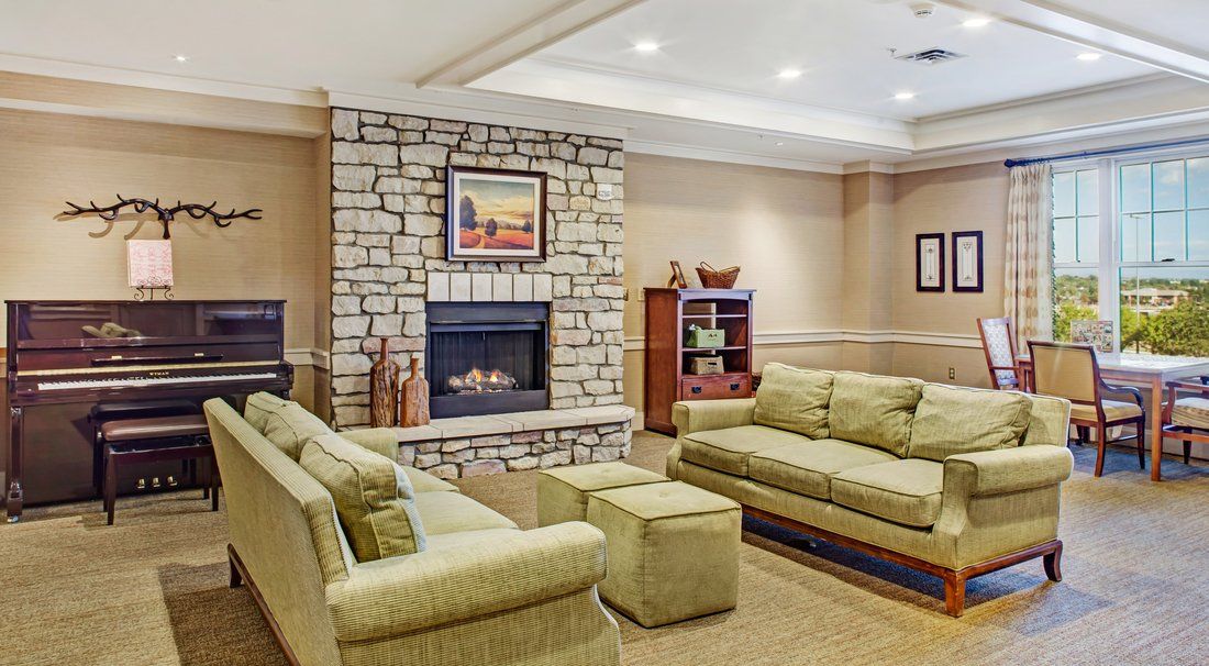 A cozy living room with sofas, a stone fireplace, and a bookshelf.
