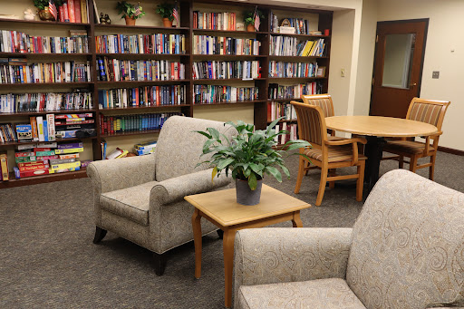 A cozy reading corner in a library, featuring comfortable chairs and a well-stocked bookshelf.
