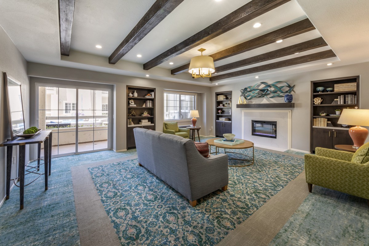 A modern living room with a cozy fireplace, stylish furniture, and exposed ceiling beams.