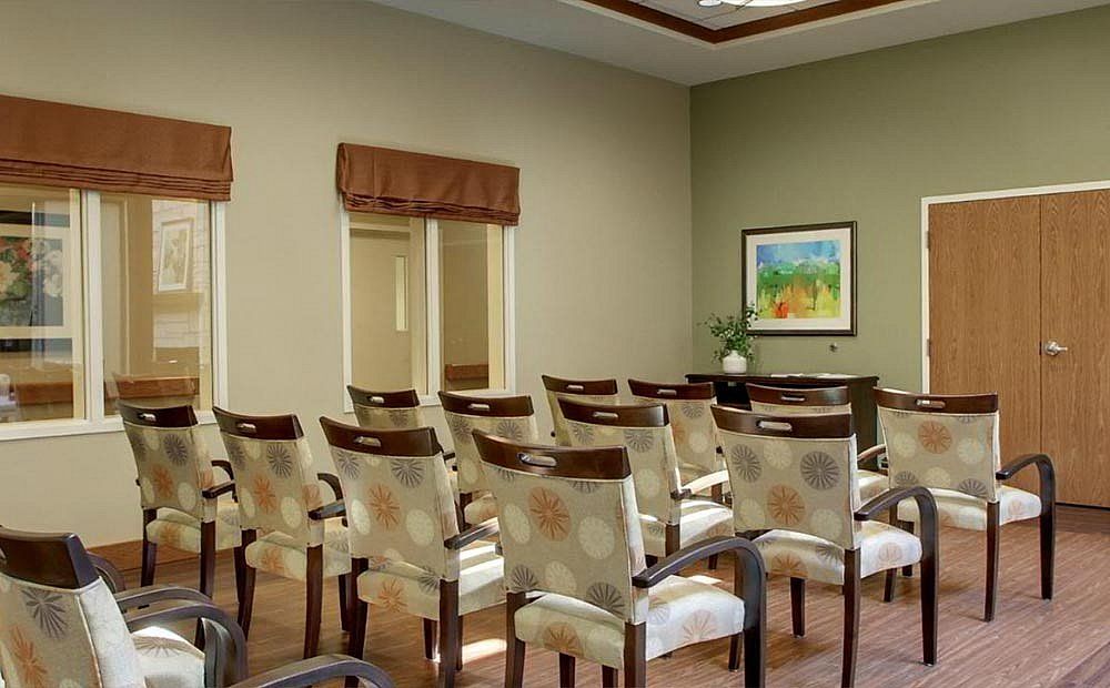 A well-arranged conference room with neatly aligned chairs and a decorative painting on the wall.