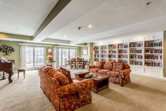 A cozy living room with a library, featuring comfortable sofas and expansive bookshelves.