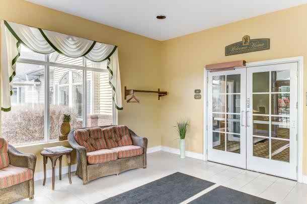 A cozy lobby area with a sofa, window with curtains, and glass doors.