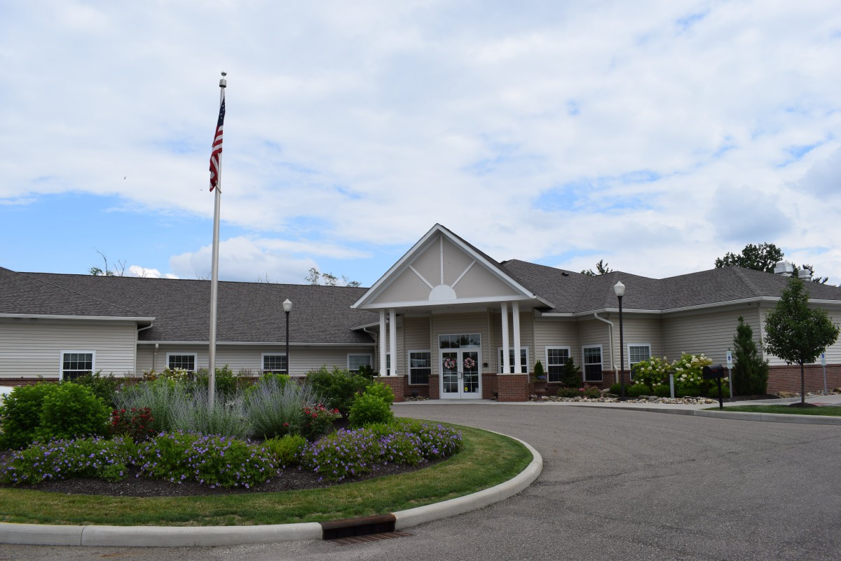 A well-maintained building with a landscaped entrance and an American flag flying outside under a cloudy sky.
