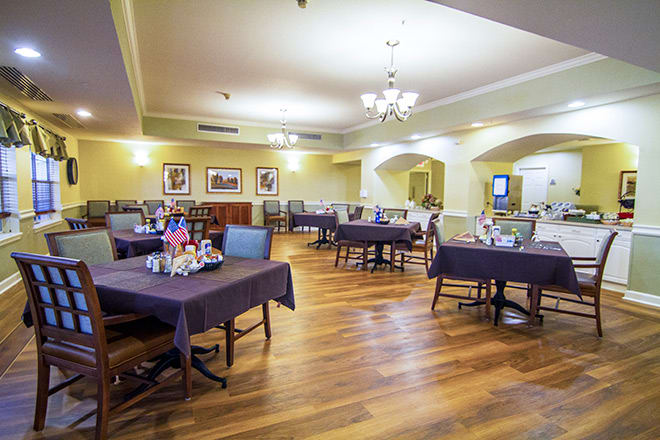 A spacious dining area set with tables and chairs, featuring a wooden floor and elegant decor.