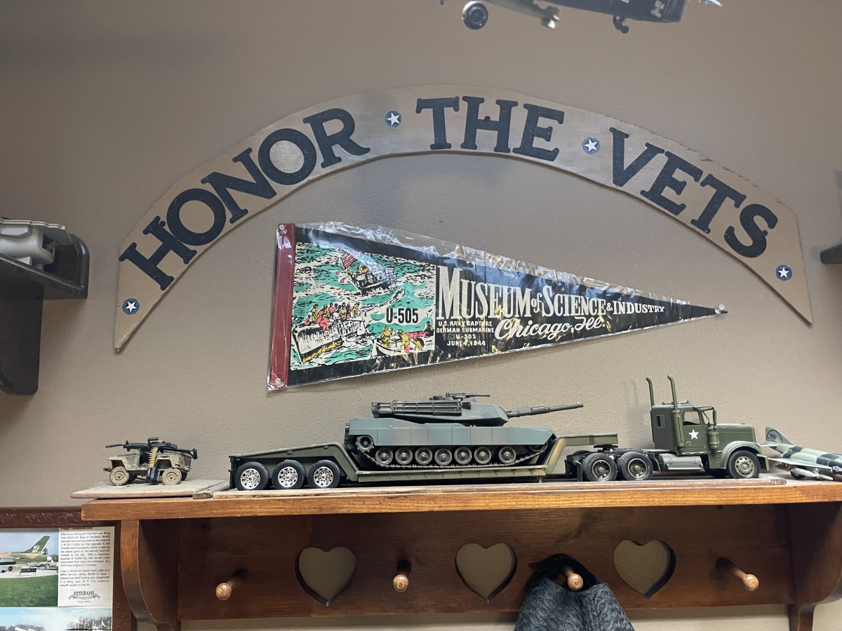 Military memorabilia display honoring veterans with model tanks and a commemorative pennant.