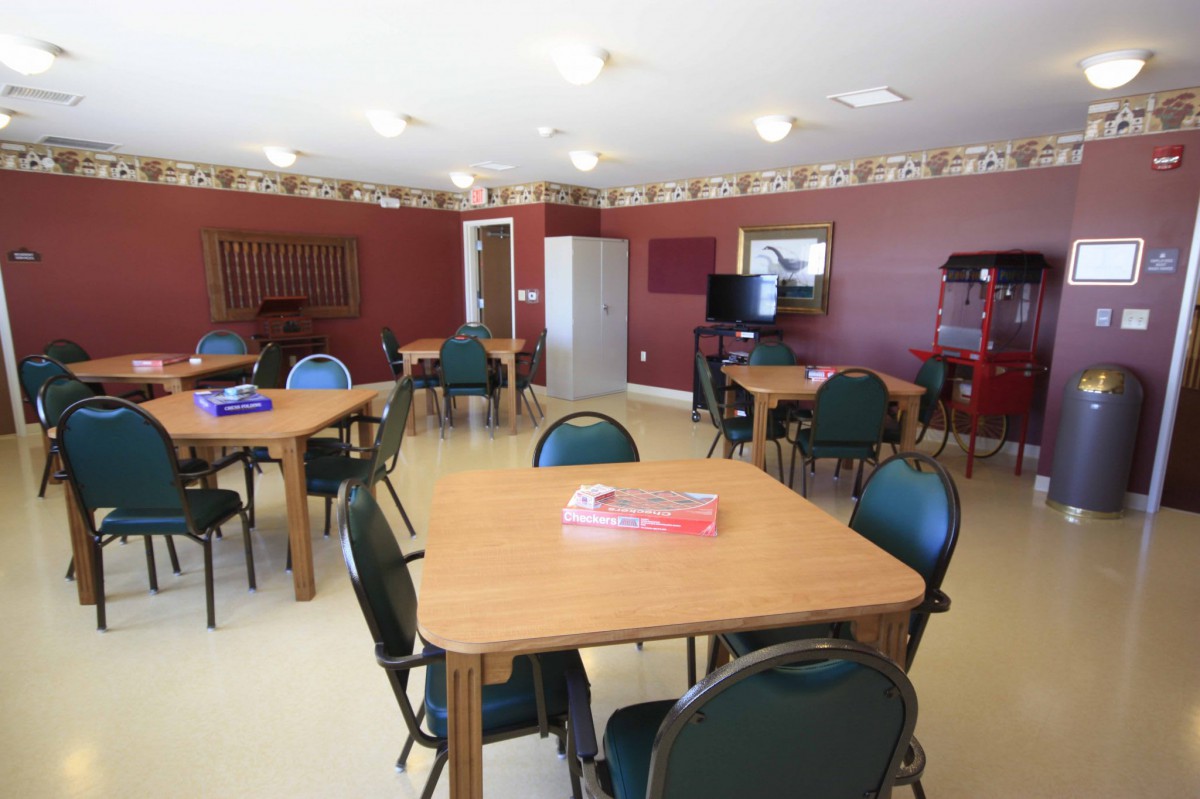 A spacious community room with tables and chairs arranged for a meeting or group activity.
