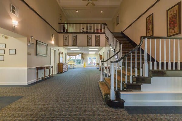 A spacious interior hallway featuring a staircase with a wooden banister and carpeted flooring.