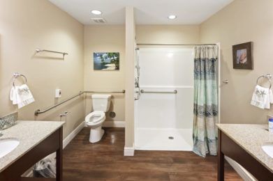 A modern, accessible bathroom with a wide shower and safety grab bars.