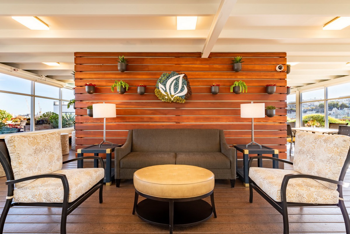 A modern lobby featuring a wooden accent wall with plants and cozy seating arrangements.