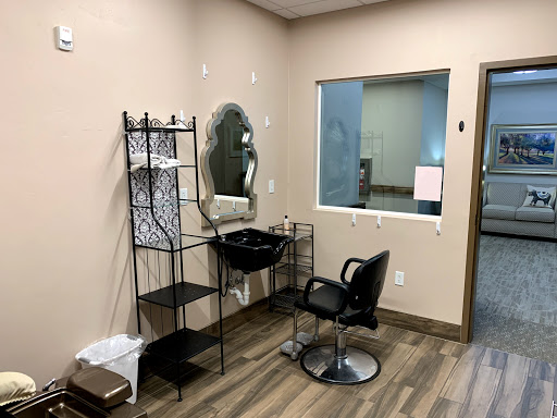 A neatly organized hair salon workspace with a barber chair, mirror, and shelving.