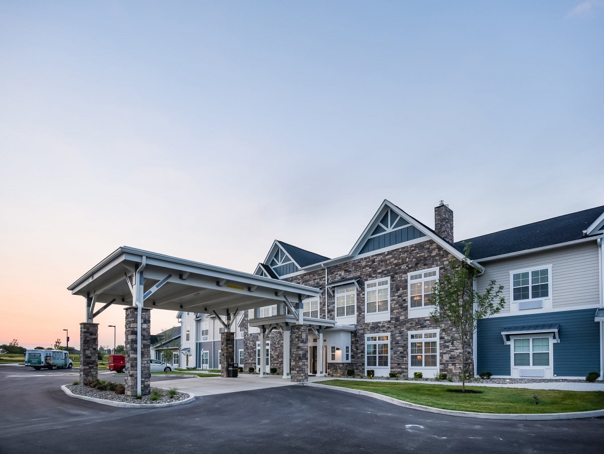 A modern residential building with a covered entrance and stone facade.