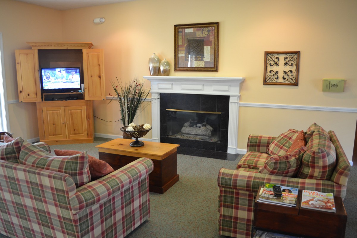 A cozy living room with a fireplace, plaid sofas, and a television.
