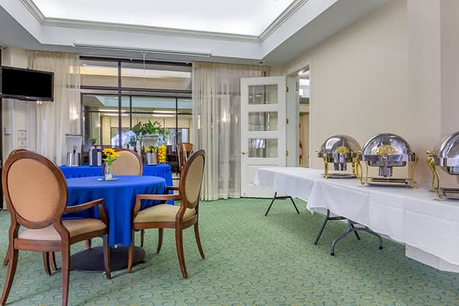 A banquet room prepared for an event with tables, chairs, and a buffet setup.